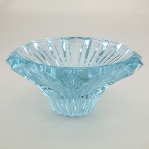 May include: A light blue, decorative glass bowl with a flared, petal-like shape. The bowl has a textured, ribbed design on the exterior and a smooth interior. The bowl is likely used for decorative purposes.