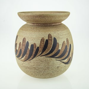 May include: A brown ceramic vase with a wide mouth and a rounded body. The vase has a black and brown leaf design.