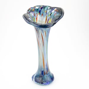 May include: A tall, blue glass vase with a wide, flared opening. The vase has a colorful, abstract design with streaks of white, orange, and green.
