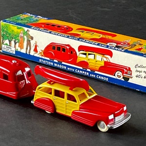 May include: A red and yellow toy station wagon with a red camper trailer attached. The wagon has a canoe on top and the box reads "Station Wagon with Camper and Canoe".