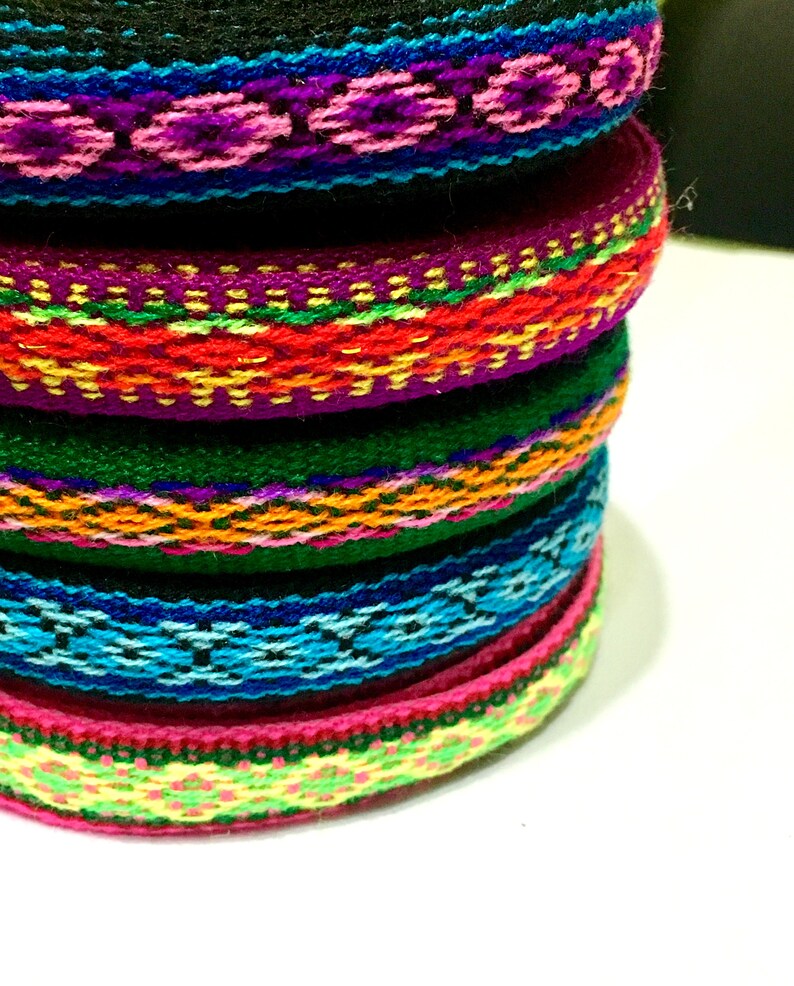 May include: A stack of colorful woven trim with intricate patterns in shades of pink, green, blue, yellow, orange, and red.