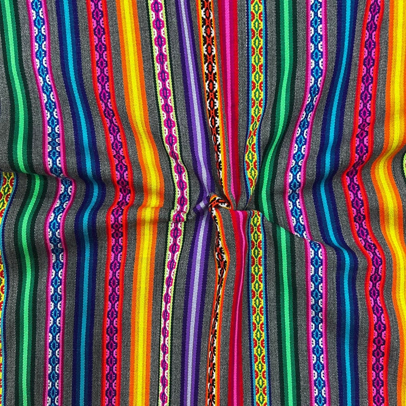 May include: Colorful striped fabric with a variety of colors, including red, orange, yellow, green, blue, purple, and pink. The fabric has a woven texture and is folded in the center.