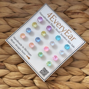 May include: A collection of colorful, iridescent plastic stud earrings arranged on a white card. The card reads "4EveryEar" and "Hypoallergenic Plastic Studs. Sensitive Skin Safe." Text also states "Handmade in Michigan. More designs here!"