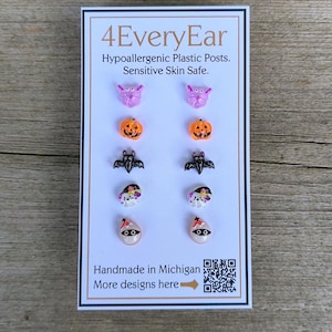 May include: A card featuring Halloween-themed stud earrings. The earrings include designs of bats, pumpkins, ghosts, and butterflies. The card reads "4EveryEar" and "Handmade in Michigan". The earrings are made with hypoallergenic plastic posts.