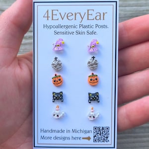 May include: A card featuring eight pairs of Halloween-themed stud earrings. Designs include witch hats, mummies, jack-o'-lanterns, black cats, and ghosts. The card reads "4EveryEar" and "Hypoallergenic Plastic Posts. Sensitive Skin Safe."