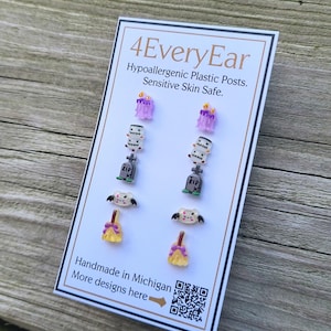 May include: A card displays six pairs of Halloween-themed earrings. The earrings include purple candles, tombstones, bats, and witch brooms. The card reads "4EveryEar" and "Handmade in Michigan."