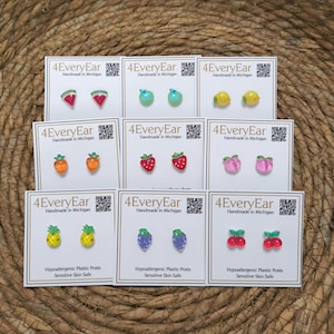 May include: A collection of fruit-themed stud earrings, including watermelon, apples, lemons, carrots, strawberries, peaches, pineapples, grapes, and cherries. Each pair is displayed on a white card with the text "4EveryEar Handmade in Michigan". The cards also state "Hypoallergenic Plastic Posts Sensitive Skin Safe".