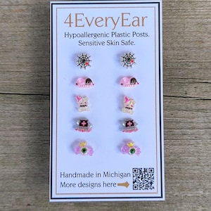 May include: A card displaying various hypoallergenic plastic post earrings. Designs include spiderwebs, pink mice, ghosts, crosses, and a pink eye with a crown. The card reads "4EveryEar" and "Handmade in Michigan."