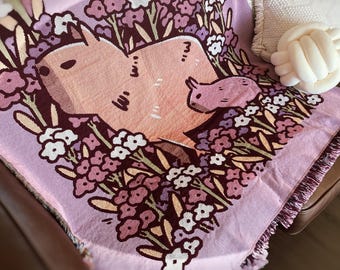 Manta tejida con capibaras y flores en color rosa de Noristudio