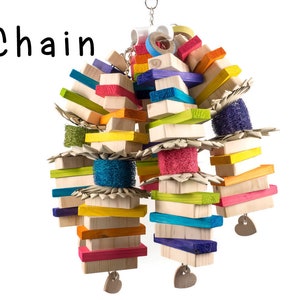 May include: A colorful wooden bird toy with a chain, featuring various shapes and textures, including wood blocks, colorful sponges, and woven straw. The toy is designed for birds to play with and features a heart-shaped charm.