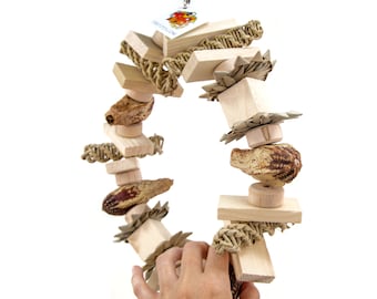 May include: A wooden bird toy with a ring shape, featuring natural materials like wood, rope, and dried fruit. The toy is designed for birds to chew and play with.