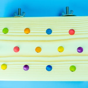 May include: A wooden toy with 12 colorful balls attached to it. The toy is designed for small animals to play with and is made of natural wood.