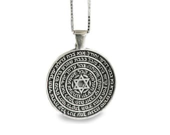May include: A silver pendant necklace with a round charm featuring a Star of David and Hebrew text. The charm is surrounded by a circle of Hebrew text.