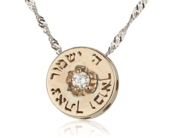 May include: A gold pendant necklace with a round charm featuring Hebrew text and a small diamond in the centre. The chain is silver.