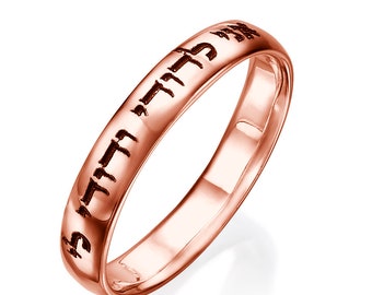 May include: A rose gold band ring with Hebrew lettering engraved around the band.