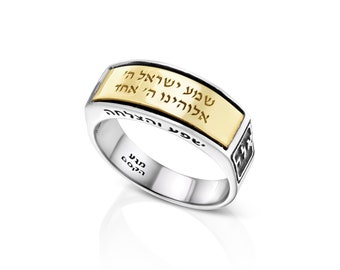 May include: A silver ring with a gold band featuring Hebrew text. The ring has a rectangular gold center and a polished silver band. The text is in gold, and the ring is set against a white background.
