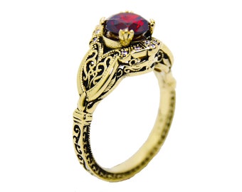 May include: A gold ring with an intricate filigree design and a large red gemstone in the center.