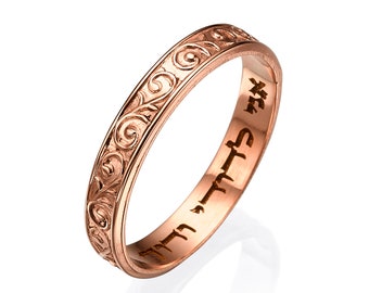 Könnte beinhalten: Ein Roségold-Bandring mit einem aufwendigen floralen Design, das auf der Außenseite graviert ist. Die Innenseite des Bandes ist mit hebräischem Text beschriftet.