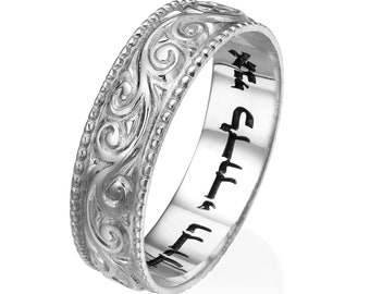 May include: A silver ring with an intricate, swirling floral pattern. The ring has a beaded border and engraved text on the inside. The ring is a classic design, suitable for various occasions.