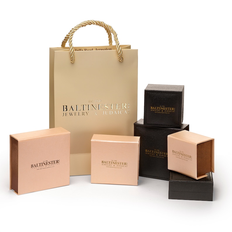 Puede incluir: Un conjunto de seis cajas con el texto "BALTINESTER: JEWELRY & JUDAICA" impreso en ellas. Las cajas son de varios tama&ntilde;os y est&aacute;n hechas de cart&oacute;n marr&oacute;n. Las cajas est&aacute;n dispuestas en forma de pir&aacute;mide. Las cajas est&aacute;n sobre una superficie blanca. Hay una bolsa de compras beige con el texto "BALTINESTER: JEWELRY & JUDAICA" impreso en ella.