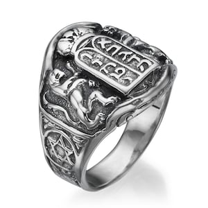 May include: A silver ring with a detailed design featuring two lions flanking a tablet with Hebrew text. The ring also has a Star of David on the side.