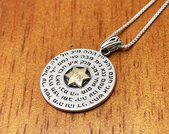 May include: A silver necklace with a round pendant featuring a six-pointed star with Hebrew text around the perimeter. The star is made of gold and has Hebrew text inside it.