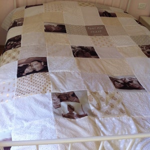 May include: A white quilt with a patchwork design featuring various photos of people. The quilt has a beige and white colour scheme and includes the text "Toldot Dia 29.5.12" in Hebrew.