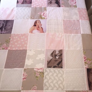 May include: A pink and white patchwork quilt featuring various images of a young girl, including a photo of her wearing a flower crown, a photo of her smiling, and a photo of her with a serious expression. The quilt also incorporates a floral pattern, a paisley pattern, and a white lace pattern. The quilt is personalised with the name "Lia" in the centre.