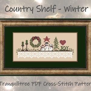Pode incluir: Padrão de ponto cruz para uma prateleira de campo com tema de inverno com uma coroa, velas, bonecos de neve, uma árvore e a palavra "ALEGRIA". O padrão é emoldurado em uma moldura marrom e dourada com um passe-partout verde.