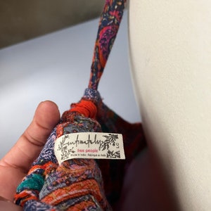 Puede incluir: Primer plano de una prenda estampada colorida con una etiqueta que dice "Intimately Free People". La tela presenta una mezcla de tonos naranja, azul y verde azulado. La prenda est&aacute; sobre un maniqu&iacute;.