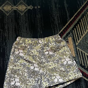 May include: White shorts with a green and gray floral pattern.