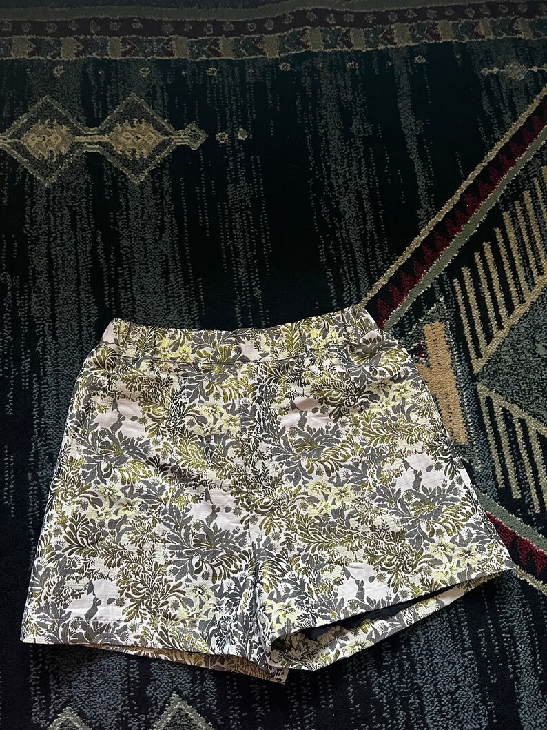 May include: White shorts with a green and gray floral pattern.