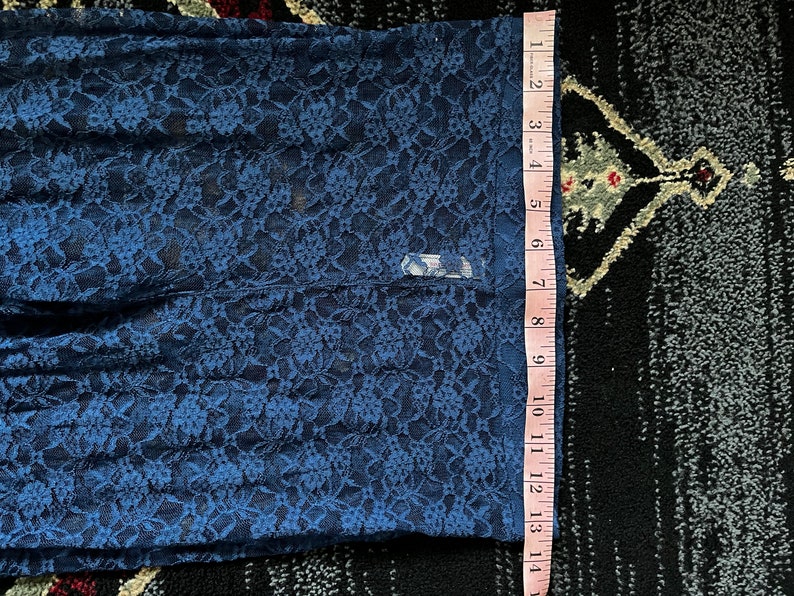 Pode incluir: Tecido de renda azul com padr&atilde;o floral. O tecido &eacute; medido com uma r&eacute;gua, mostrando um comprimento de 35,5 cm.