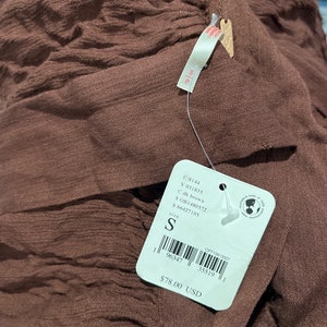 May include: A brown, textured, fabric garment with a price tag that reads "&pound;78.00". The tag also includes the size "S" and the product code "OB1480572".
