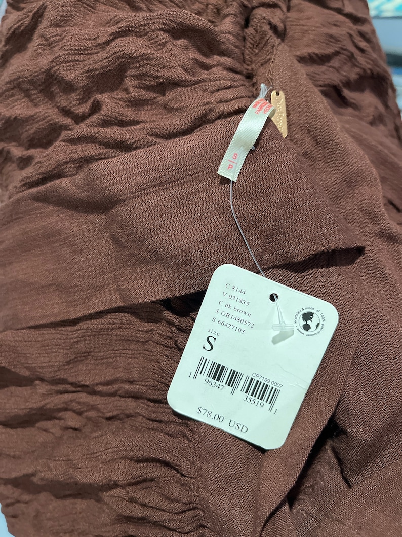 May include: A brown, textured, fabric garment with a price tag that reads "&pound;78.00". The tag also includes the size "S" and the product code "OB1480572".