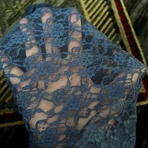 Pode incluir: Close-up de um tecido de renda azul escuro com um padr&atilde;o floral.