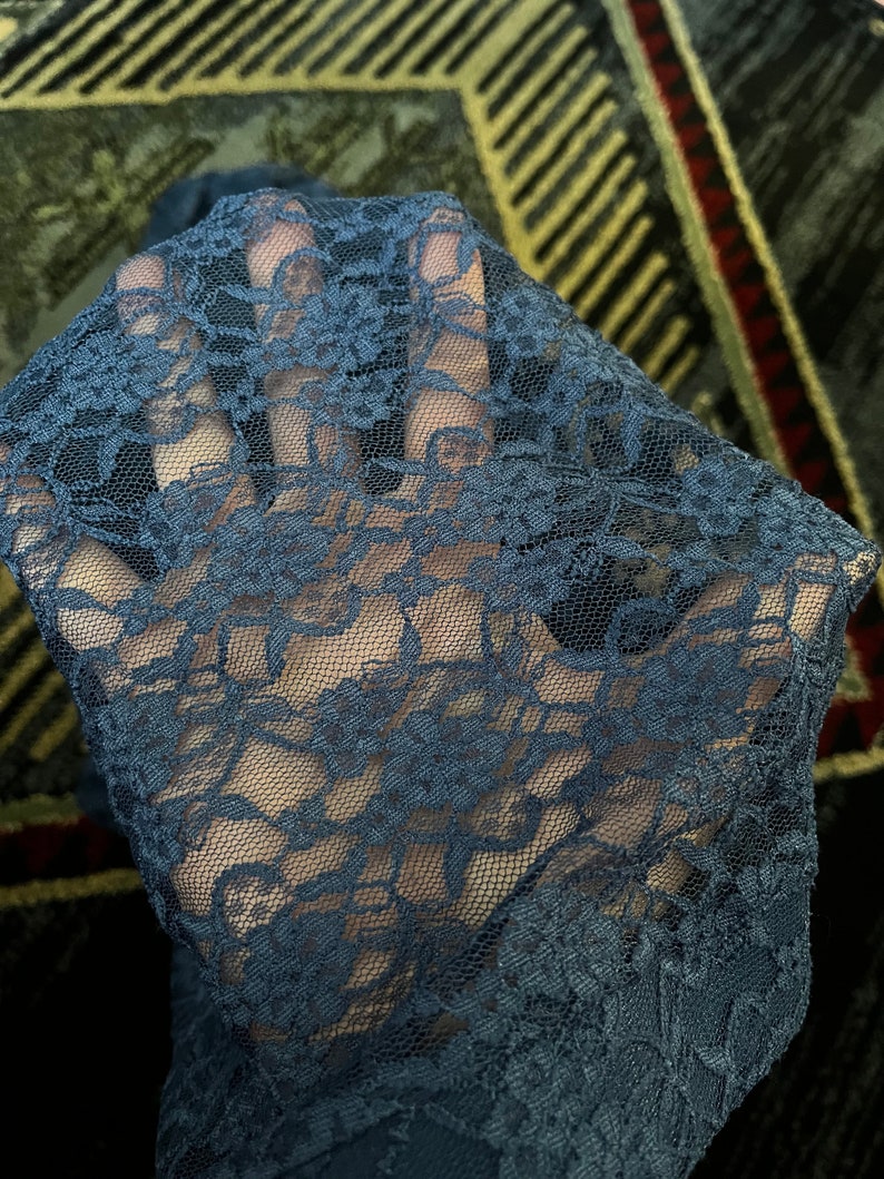 Pode incluir: Close-up de um tecido de renda azul escuro com um padr&atilde;o floral.