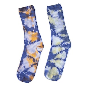 May include: A pair of tie-dye socks. One sock features a pattern of blue, yellow, and orange swirls, while the other has a similar design with blue and yellow hues. The socks are made of a ribbed knit material.