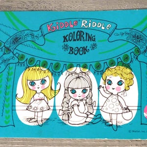 May include: Vintage "Kiddle Riddle Koloring Book" cover. The teal cover features three cartoon girls in ovals, with the title in pink and yellow. The Mattel logo is in the bottom right corner.