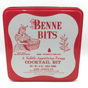 May include: A vintage red and white Benne Bits tin. The tin features a woman in a polka dot dress holding a basket. Text on the tin reads "Benne Bits" and "A Subtle-Appetizing-Tangy Cocktail Bit". Net weight is 8 oz.