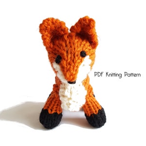 Puede incluir: Un juguete de zorro de punto naranja con detalles blancos en el pecho y detalles negros en las patas. Patrón de tejido PDF.