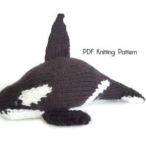 Könnte beinhalten: Ein gestricktes schwarzes und weißes Orca-Wal-Plüschtier. PDF-Strickmuster.