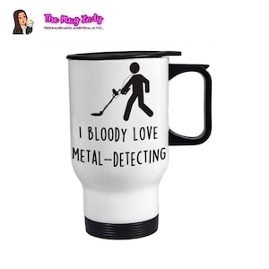 May include: White travel mug with a black lid and handle. The mug has a black silhouette of a person holding a metal detector with the text "I BLOODY LOVE METAL-DETECTING".