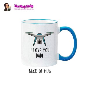 Op de afbeelding: Witte keramische mok met een blauwe rand en handvat. De mok heeft een drone-afbeelding en de tekst "I LOVE YOU DAD!". De achterkant van de mok heeft de tekst "BACK OF MUG".