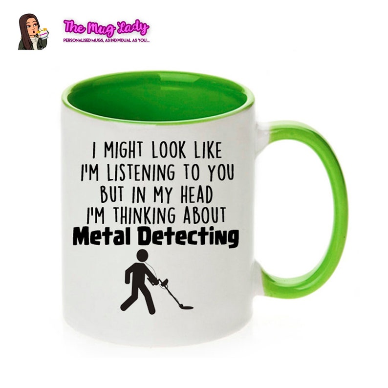 May include: White ceramic mug with a green rim and handle. The mug has a black graphic of a person walking with a metal detector and the text "I might look like I'm listening to you but in my head I'm thinking about Metal Detecting."