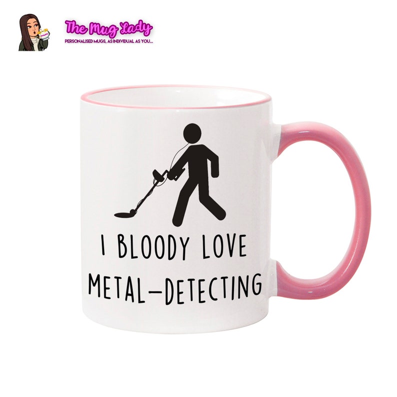 May include: White ceramic mug with a pink rim and handle. The mug features a black stick figure holding a metal detector and the text "I BLOODY LOVE METAL-DETECTING".