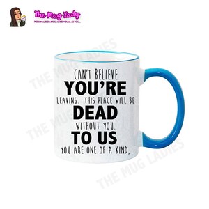 May include: White ceramic coffee mug with a blue rim and handle. The mug has black text that reads "Can't believe you're leaving. This place will be dead without you. To us. You are one of a kind."