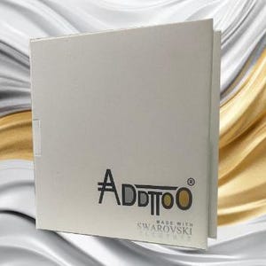 Puede incluir: Caja de cart&oacute;n blanca con el logotipo "Addtoo" impreso en negro y el texto "Made with Swarovski Elements" impreso en gris.