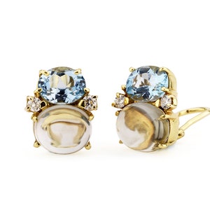 May include: A pair of gold earrings with a blue gemstone and a white shell-like gemstone. Each earring has a small diamond on either side of the blue gemstone.
