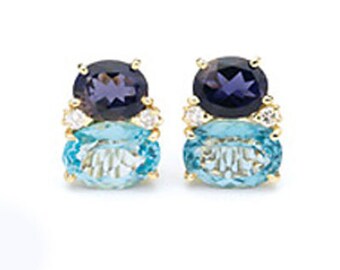 May include: A pair of gold earrings with blue and purple gemstones. The earrings feature a larger oval-shaped blue gemstone surrounded by smaller round white gemstones and a smaller oval-shaped purple gemstone.
